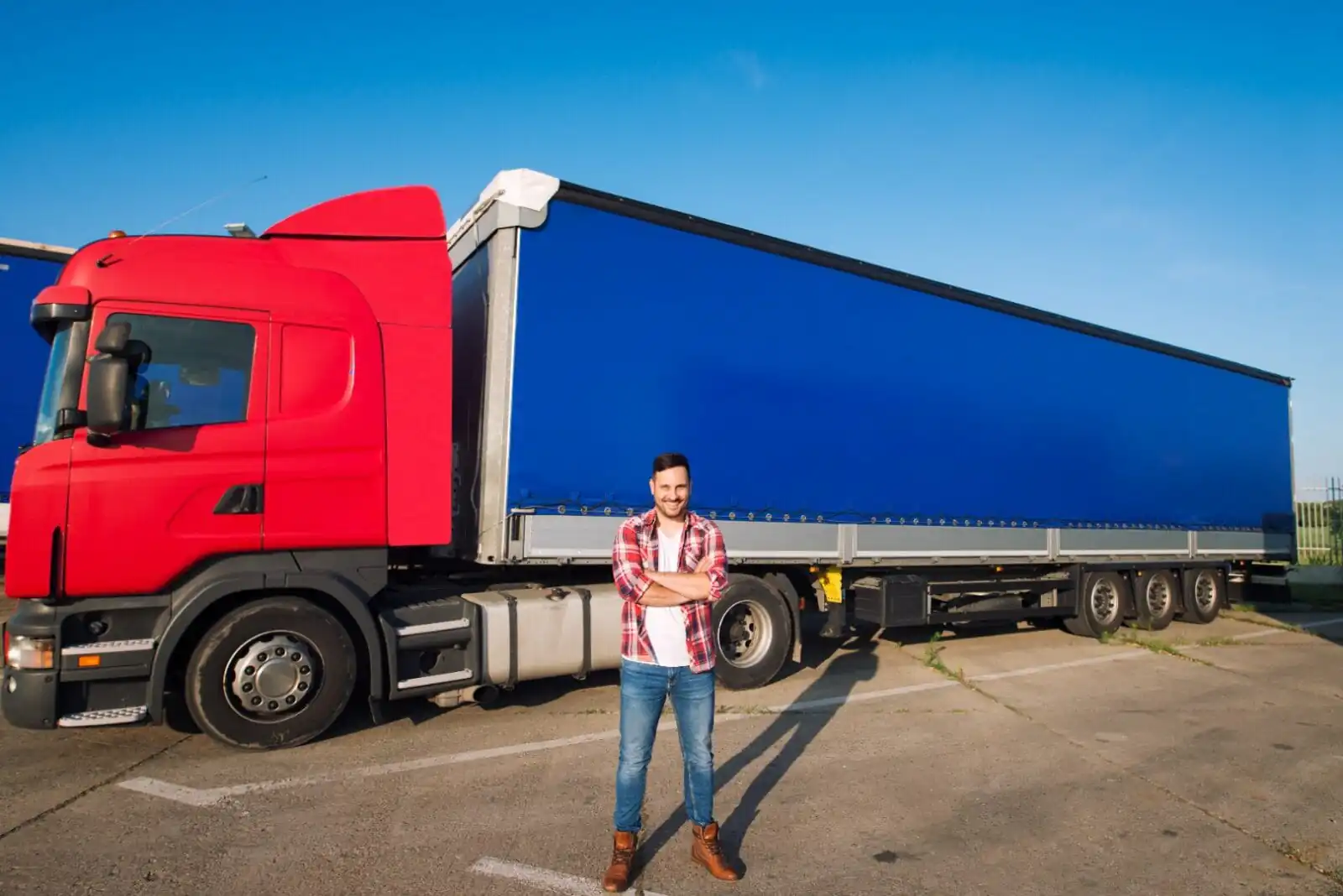 un barbat care zambeste avand in spatele sau un tir de transport marfa care are Asigurare ROTR